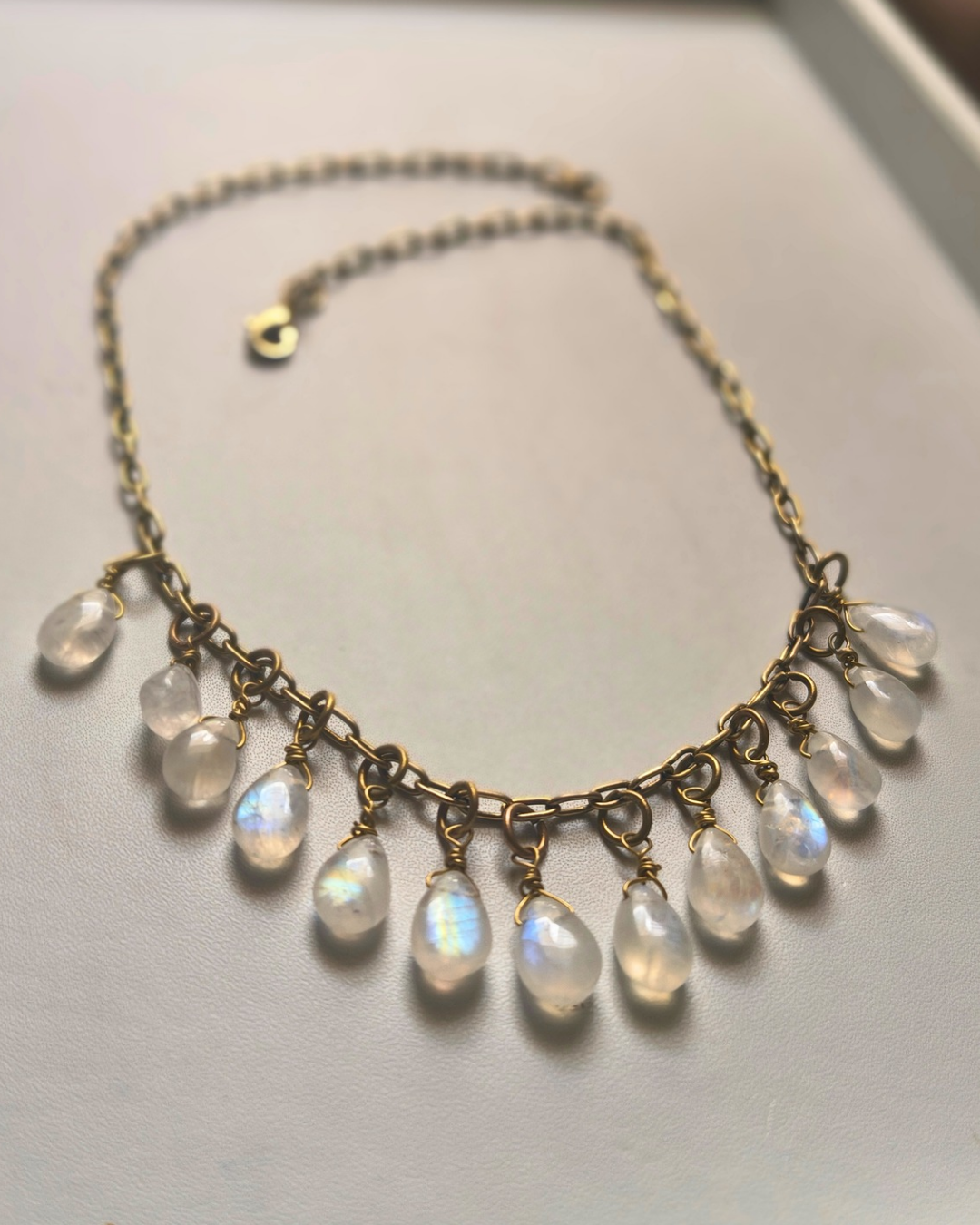 Artisan handmade rainbow moonstone necklace with delicate dangling gemstone drops and celestial inspired design.
