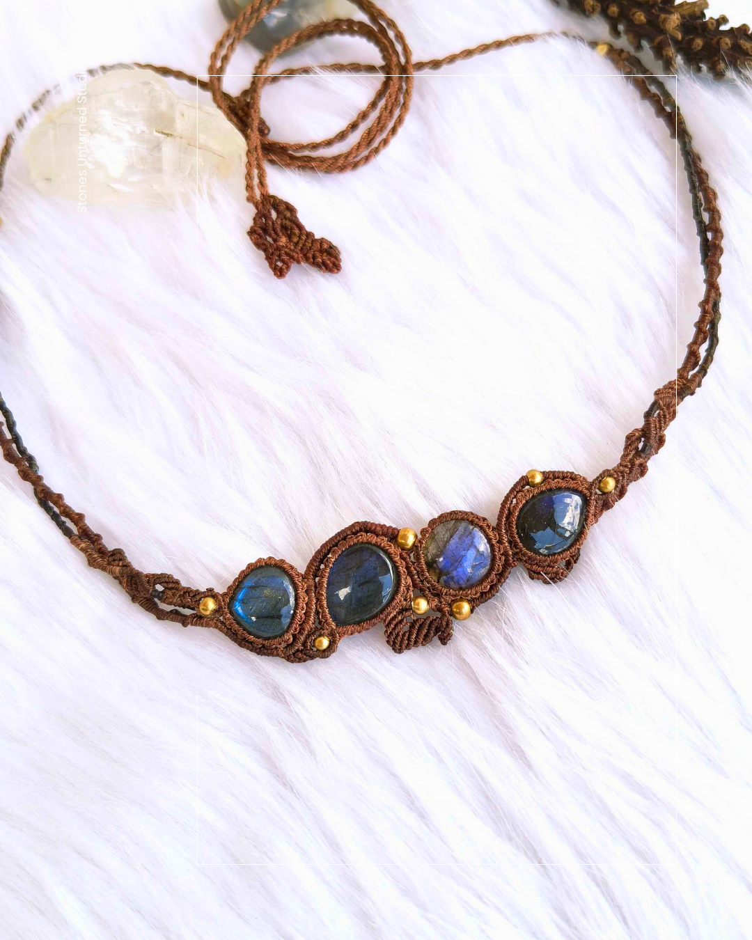 Necklace with blue labradorite gemstones and brass accents on a white fabric background