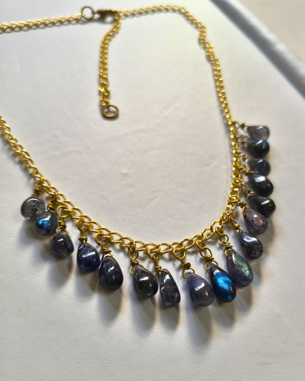 Close-up of natural labradorite gemstone drops showing vibrant blue flash on a handcrafted brass chain necklace.