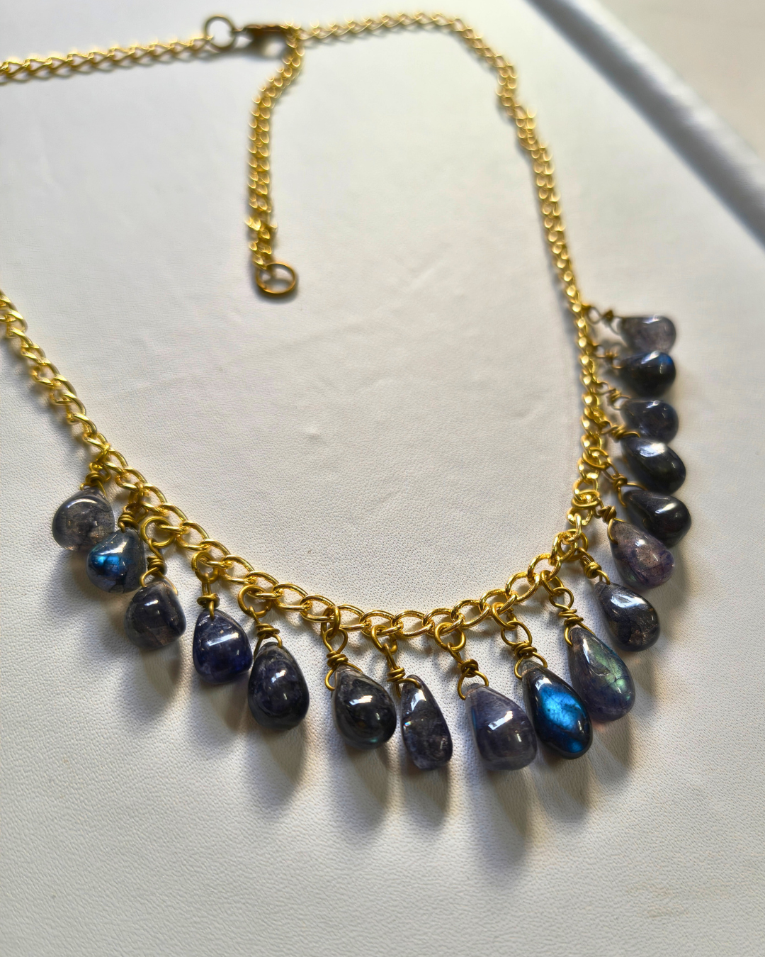 Close-up of natural labradorite gemstone drops showing vibrant blue flash on a handcrafted brass chain necklace.