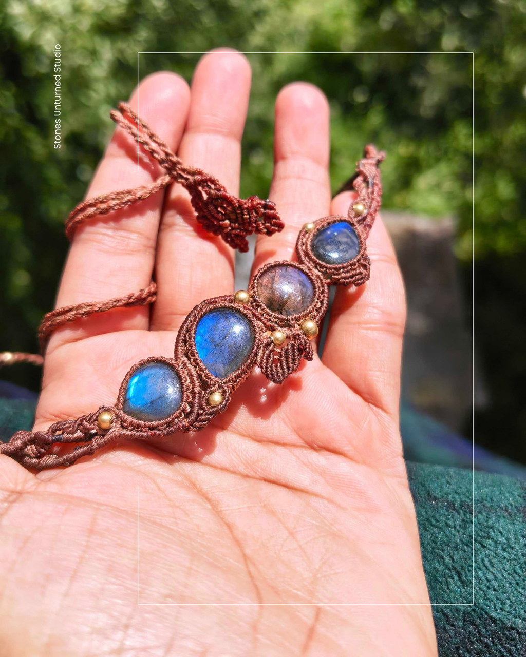 Hand holding a necklace with blue stones and Brass accents and macrame design