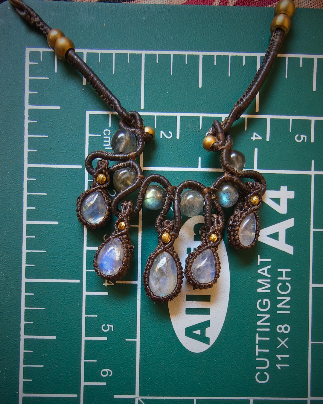 Adjustable boho macrame necklace with moonstone drops and brass beads on measurement mat for actual size