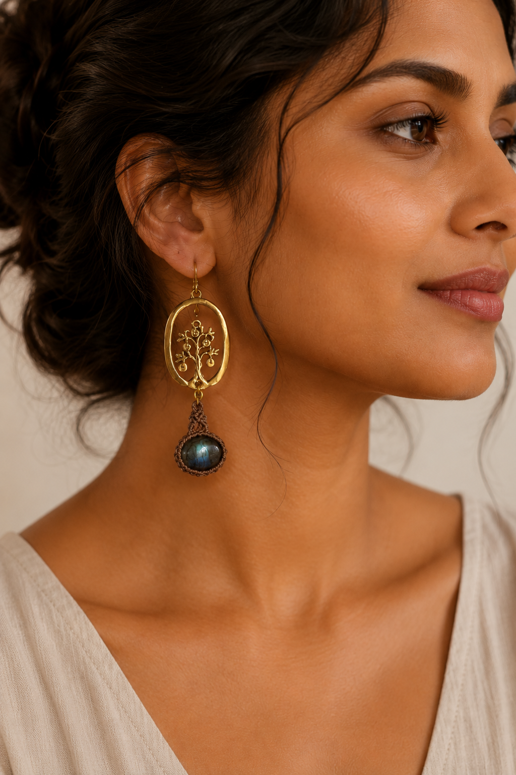 Woman styling handmade bohemian labradorite dangle earrings with polished brass tree design