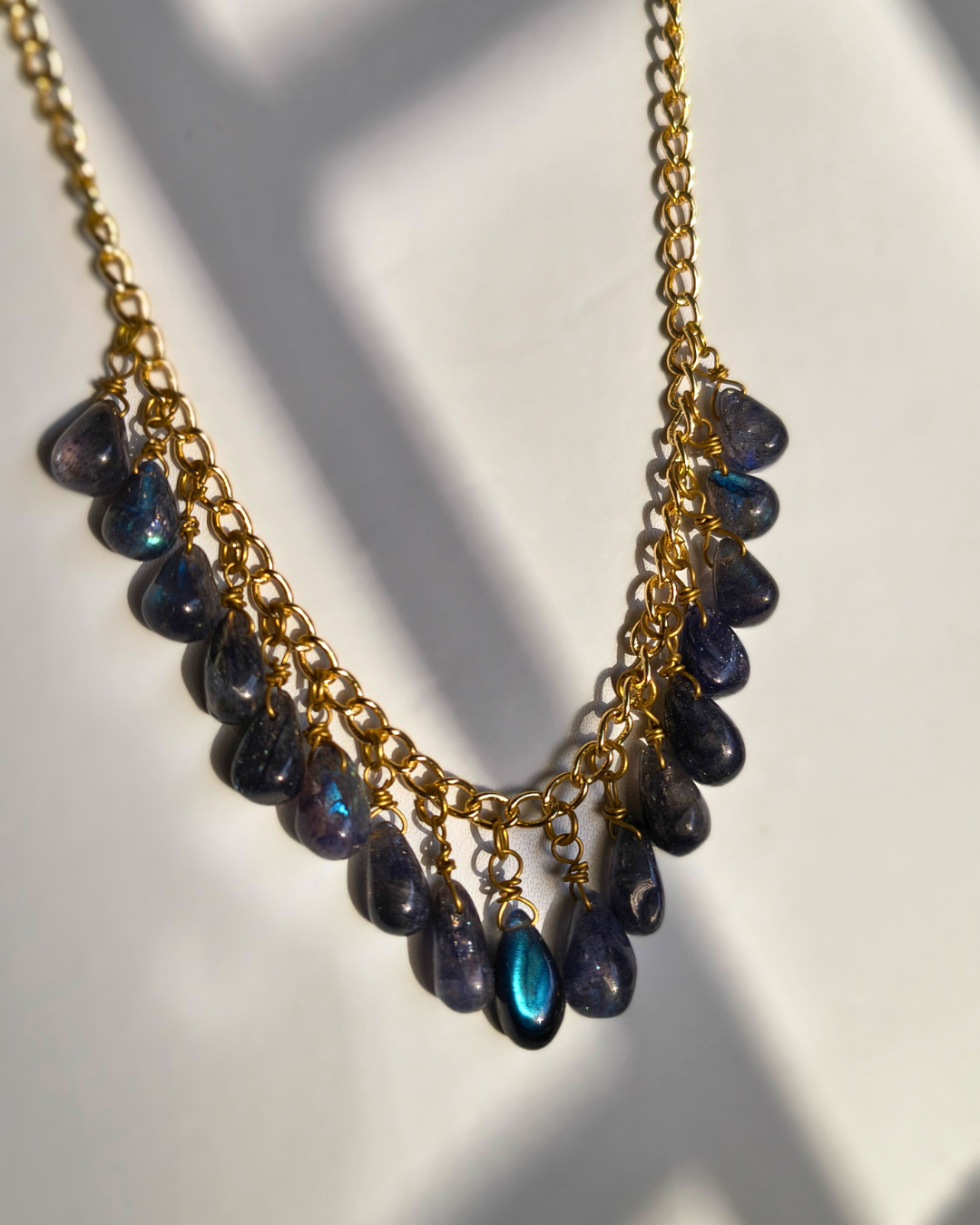 Necklace with gold plated brass chain and blue labradorite beads on a white background