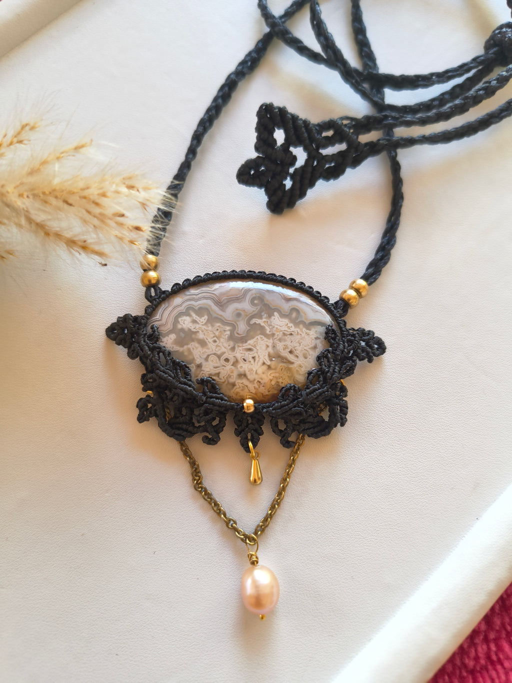 Crazy lace agate macramé locket necklace with pearl dangle from Demeter Collection, flat lay