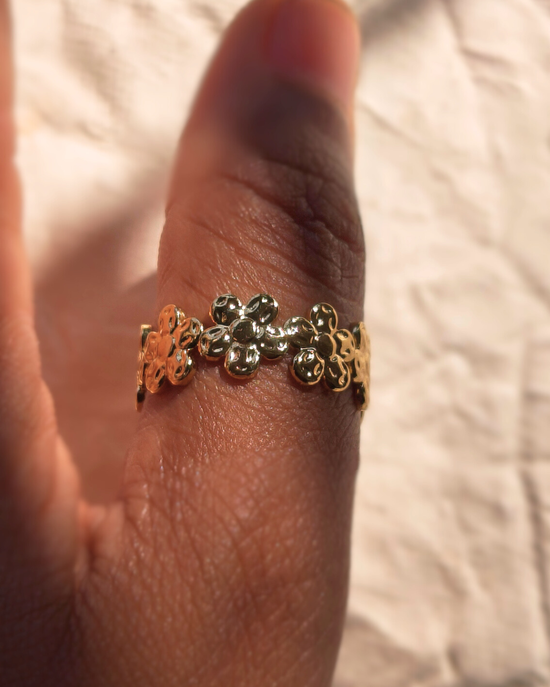 Adjustable gold ring with multiple small flowers for stacking.