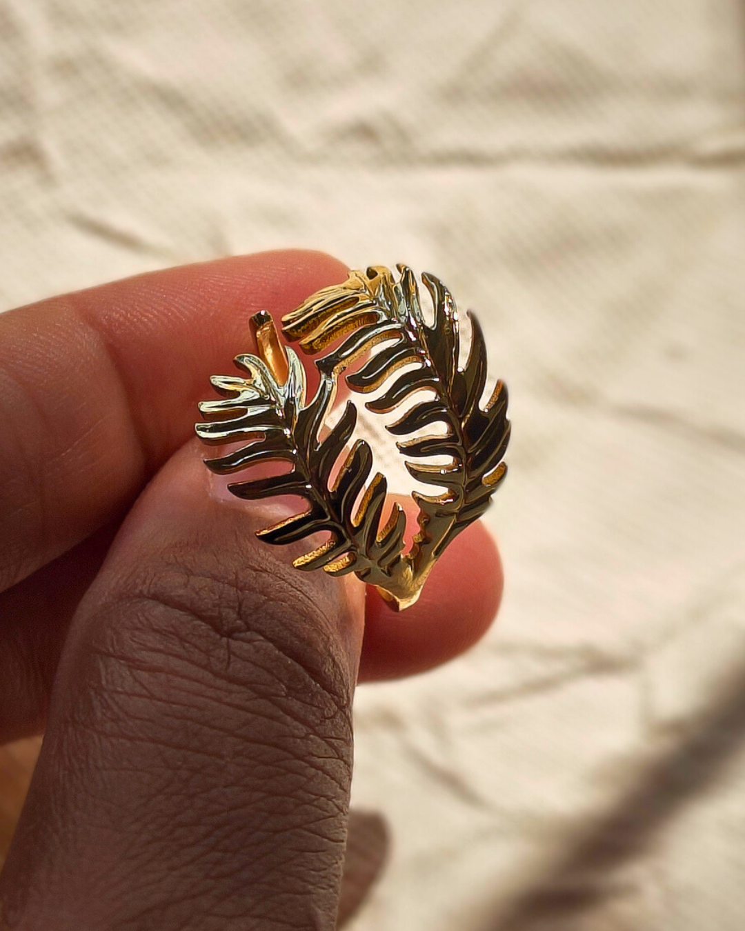Close up of gold fern leaf ring showing delicate botanical details.