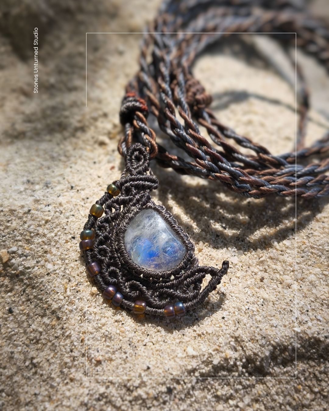 Necklace with a moonstone pendant half moon design on a sandy surface