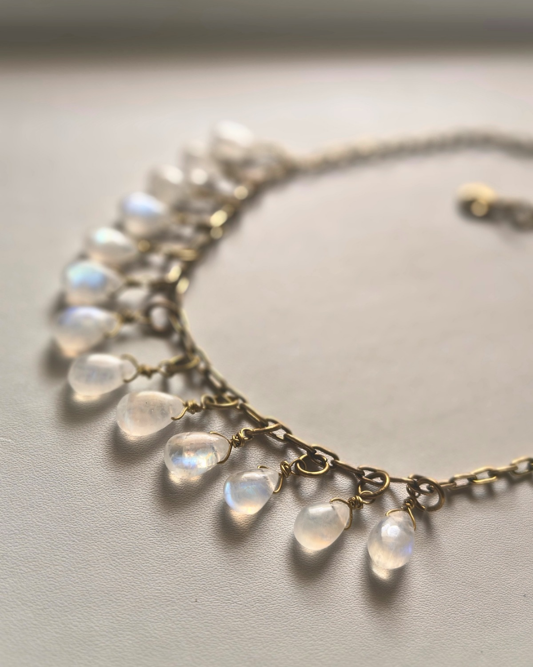 High fire rainbow moonstone necklace featuring glowing natural gemstone drops hand wrapped onto antique brass chain.