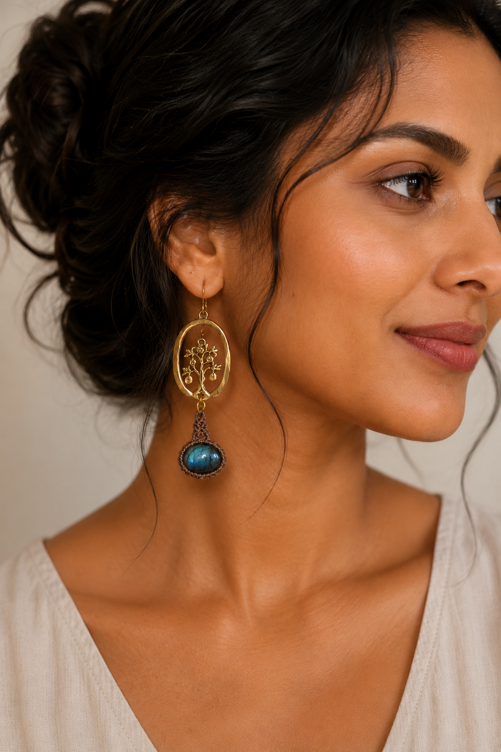 Close-up portrait of woman wearing artisan brass macramé earrings with natural labradorite stones