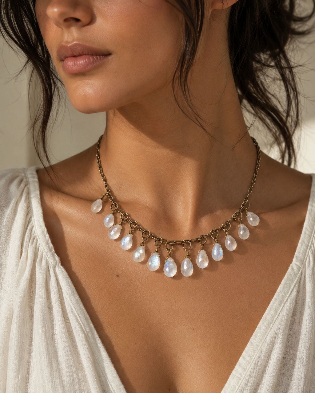 Close-up of handmade moonstone drop necklace showing glowing rainbow flashes and antique brass chain detailing.