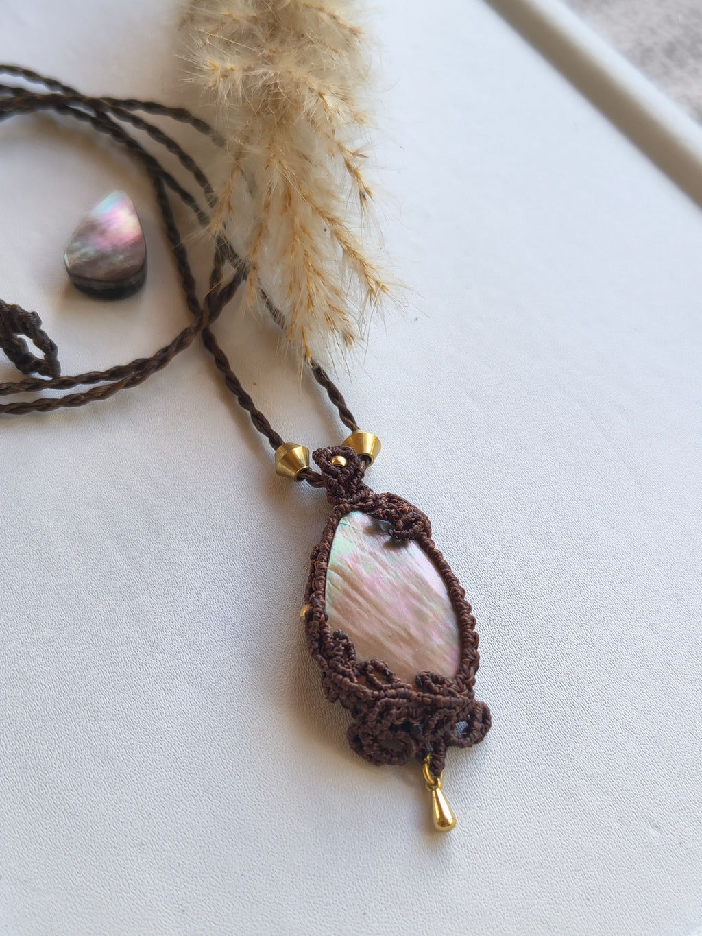 Mother of pearl pendant styled with leaves design handmade macrame jewelry top view and brass dangle and beads