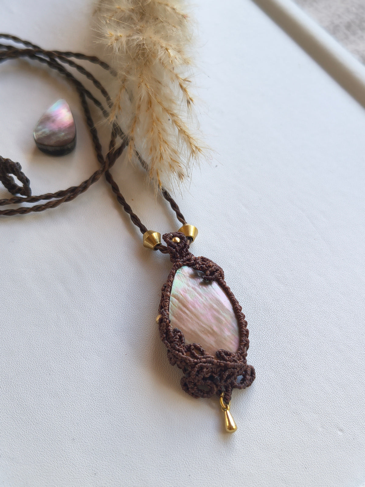 Mother of pearl pendant styled with leaves design handmade macrame jewelry top view and brass dangle and beads