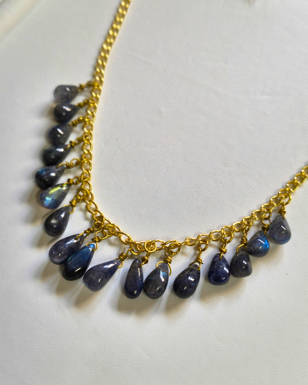 Necklace with gold chain and blue teardrop-shaped beads on a white background