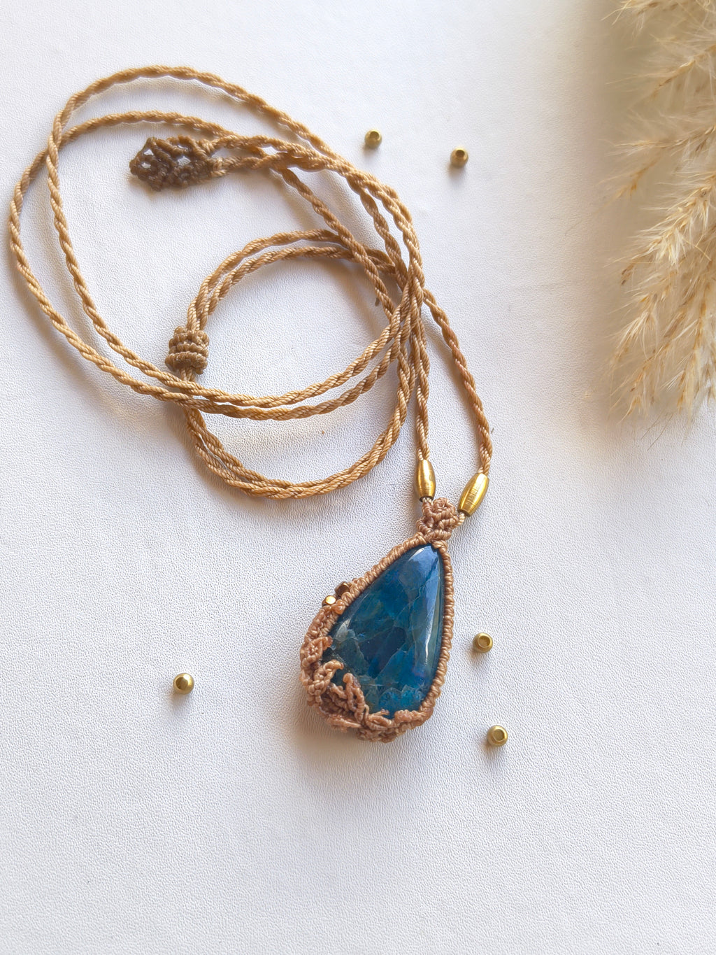 Top view of Natural blue apatite teardrop pendant necklace with beige adjustable chord and end details. 