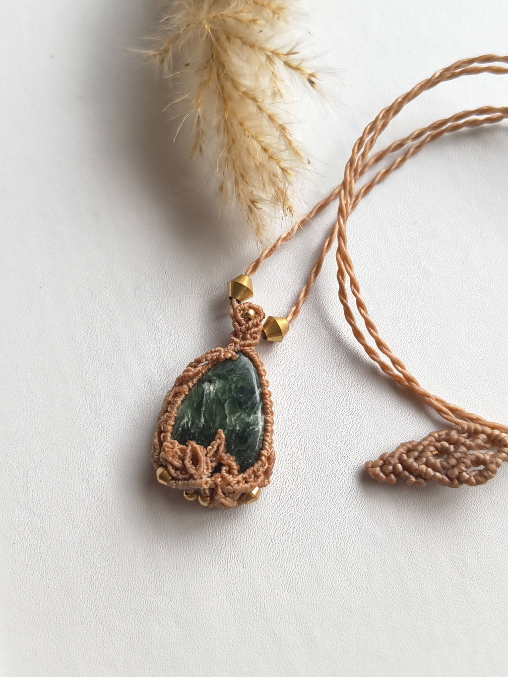 Seraphinite necklace shown with hand for scale, approx 3 cm pendant and dried leaves details and end details. 