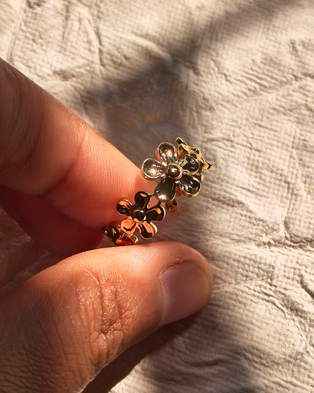 Stackable gold ring with detailed flower design and elegant finish.
