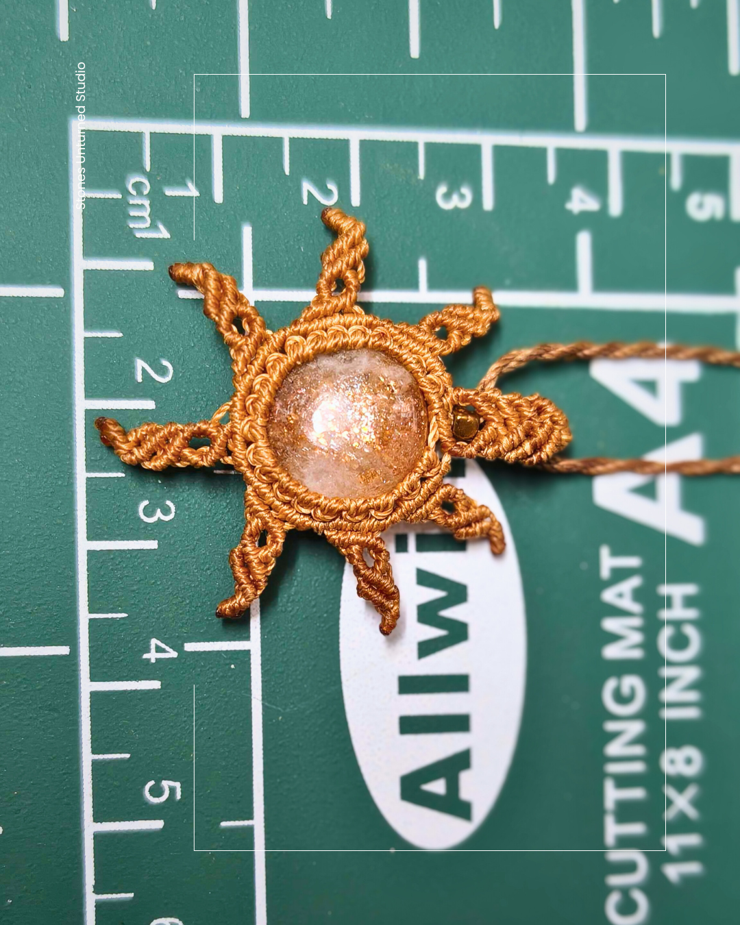Sun-shaped handmade natural gemstone jewelry on a cutting mat with measurement markings