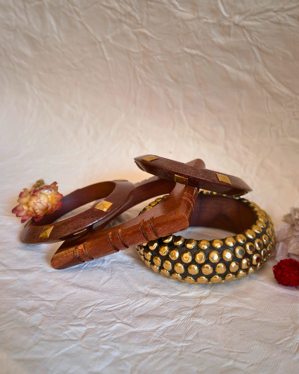 Set of four wooden bangles with brass accents placed on neutral fabric.